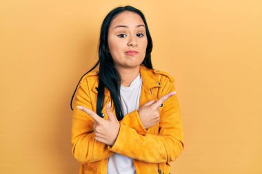 Burnu delinmiş, sarı deri ceketli, iki tarafı da parmaklarıyla gösteren güzel İspanyol bir kadın. Farklı yönlerden farklı. 