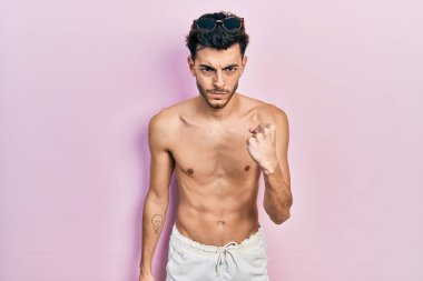 Genç İspanyol adam mayo giyiyor kızgın ve kızgın yumruk kaldırıyor öfkeyle bağırırken. öfke ve agresif konsept. 