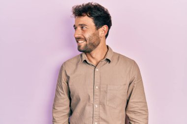 Sakallı, rahat gömlekli, rahat bir görünüm takınan, doğal yüzlü ve kendinden emin gülümseyen yakışıklı bir adam.. 