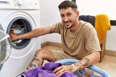 Genç İspanyol adam çamaşır odasında çamaşır makinesi kullandığından emin.