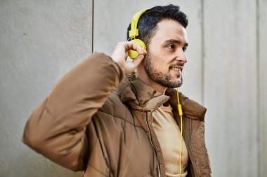Şehirde kulaklık takarak mutlu gülümseyen genç İspanyol adam..