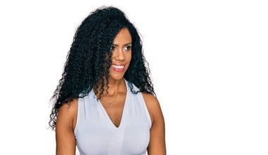 Orta yaşlı Afro-Amerikalı kadın kolsuz tişörtlü, gündelik tarzda giyiniyor. Yüzünde gülümseme ve doğal ifadeyle yan yana bakıyor. Kendinden emin gülen. 