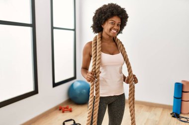 Genç Afrikalı Amerikalı kadın gülümsüyor spor merkezinde kendine güvenen bir halat tutuyor.