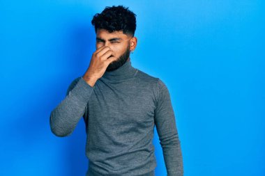 Balıkçı yaka kazak giyen Arap adam pis ve iğrenç bir koku alıyor. Nefesini burnunda tutuyor. Kötü kokuyor. 