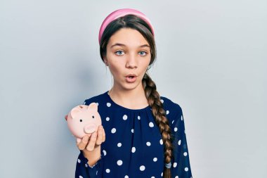 Genç esmer kız kumbarayı elinde tutuyor. Korkmuş ve ağzı açık kalmış, şaşırmış ve şaşırmış. 