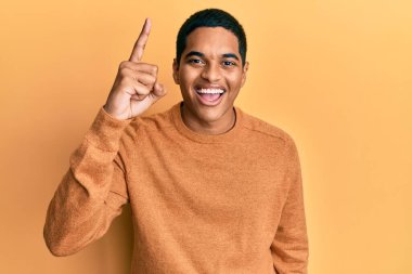 Kış süveteri giyen genç, yakışıklı İspanyol adam başarılı bir fikri işaret ediyor. Heyecanlı ve mutlu. Bir numara.. 