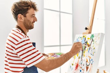 Genç İspanyol adam resim stüdyosunda kendine güvenen gülümsüyor.