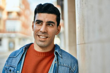 Genç İspanyol adam gülümseyerek şehirde mutlu mesut dikiliyor..