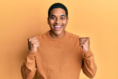 Sıradan bir kazak giyen genç, yakışıklı İspanyol adam kollarını kaldırıp, gözlerini açarak başarıyı kutluyor ve şaşırıyor. Kazanan konsept. 