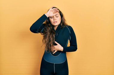 Genç İspanyol kız dalgıç neoprene üniforması giyiyor hastalık ve ateş için alnına dokunuyor, grip ve soğuk algınlığı, virüs hastalığı 