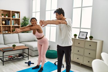 Genç Latin sporcu çift gülümseyerek evde mutlu bir antrenman yapıyor..