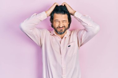 Orta yaşlı, günlük kıyafetler giyen, baş ağrısı çeken, çaresiz ve stresli bir adam. Ağrı ve migren yüzünden. Eller başının üstünde.. 