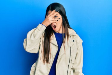 Deri ceket giyen genç İspanyol kadın şok içinde yüzünü ve gözlerini eliyle kapatıyor, parmaklarından korkuyla bakıyor. 