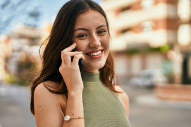 Beyaz kız gülümsüyor. Şehirdeki akıllı telefondan konuşuyor..