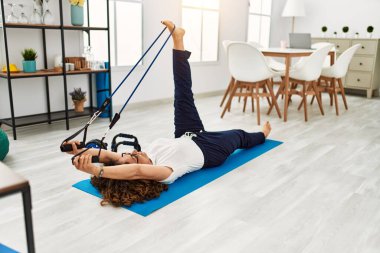 Olgun İspanyol kadın evdeki oturma odasında lastik bantlarla egzersiz yapıyor.