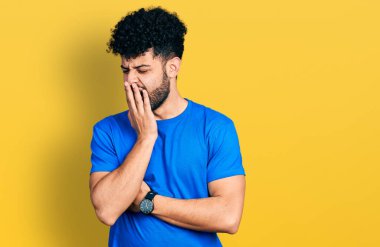 Sakallı, sıradan mavi tişörtlü genç bir Arap, ağzıyla esnemekten sıkılmış. Huzursuz ve uykulu.. 