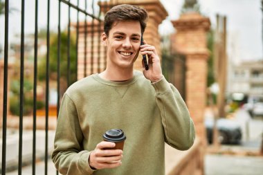 Genç İspanyol adam akıllı telefondan konuşuyor. Şehirde kahve içiyor..