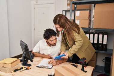 Kadın ve erkek işçiler akıllı telefondan konuşuyor ve ofiste dokunmatik ped kullanıyorlar.
