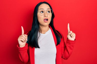 Havalı bakışlar ve gözlük takan güzel İspanyol kadın şaşırmış ve şaşırmış bir şekilde parmaklarıyla işaret ediyor ve kollarını kaldırıyordu.. 