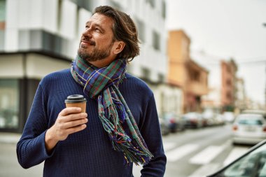 Orta yaşlı yakışıklı adam kasabada bir fincan kahve içiyor.