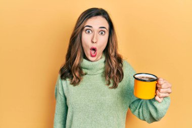 Genç İspanyol kız bir fincan kahve içiyor. Korkmuş ve ağzı açık, şaşırmış ve şaşırmış. 
