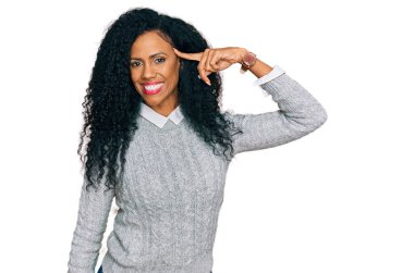 Orta yaşlı Afro-Amerikalı kadın gündelik kıyafetler giyip gülümsüyor. Tek parmakla işaret ediyor. Harika bir fikir ya da düşünce. 