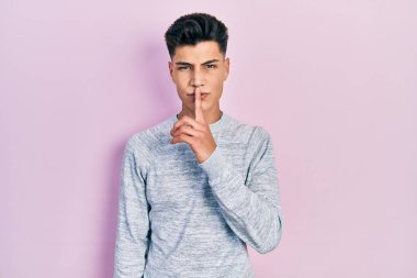 Gündelik kıyafetler giyen genç İspanyol adam parmakları dudaklarında sessiz olmak istiyor. sessizlik ve gizli konsept. 