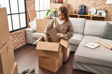Beyaz bir kadın yeni evinde kendine güvenen bir paket paketliyor.