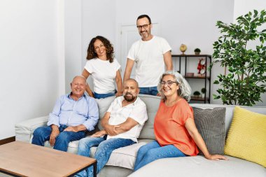 Orta yaşlı arkadaşlar evdeki kanepede mutlu mesut oturuyorlar..