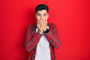 Gündelik kıyafetler giyen genç İspanyol adam yanlışlıkla elleri ile ağzını kapatırken şok oldu. gizli kavram. 