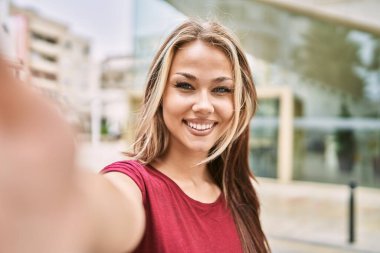 Genç beyaz kız mutlu bir şekilde gülümsüyor şehrin kamerasının önünde selfie çekiyor..