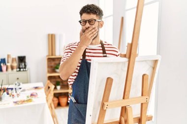 Sanat stüdyosundaki Arap genç adam, ağız kaplamaktan sıkılmış. Huzursuz ve uykulu.. 