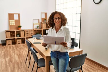 Ofiste çalışırken gülümseyen orta yaşlı İspanyol kadın.