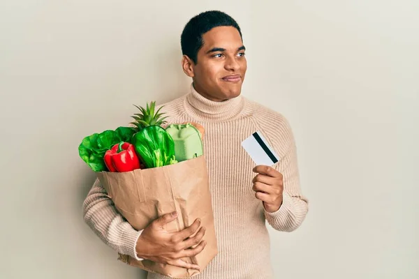 Joven Hombre Hispano Guapo Sosteniendo Comestibles Tarjeta Crédito Sonriendo Mirando —  Fotos de Stock