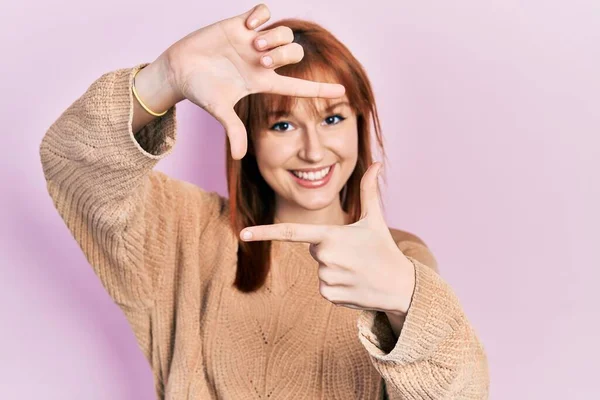 红头发的年轻女人穿着休闲地冬季毛衣 微笑着用双手和手指做框架 脸上带着幸福的表情 创意与摄影概念 — 图库照片