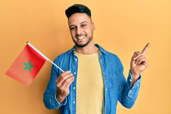 Mladý Arabský Muž Drží Morocco Vlajku Úsměvem Šťastný Ukazuje Rukou — Stock fotografie