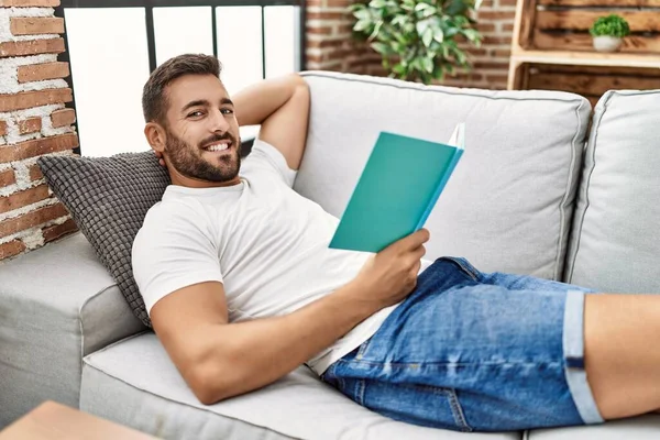 Joven Hispano Sonriendo Confiado Leyendo Libro Casa —  Fotos de Stock