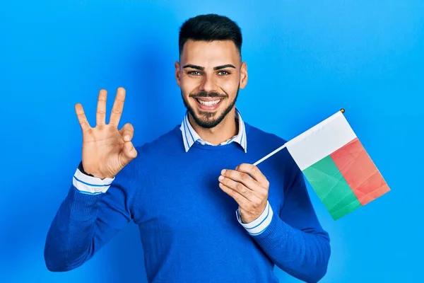 Young Hispanic Man Beard Holding Madagascar Flag Doing Sign Fingers — Stock Photo, Image