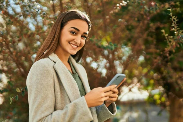 若いですヒスパニック系の女の子笑顔幸せな使用してスマートフォンで市 — ストック写真