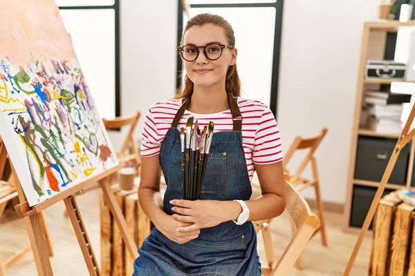 Mujer Joven Sonriendo Confiada Sosteniendo Pinceles Estudio Arte — Foto de Stock