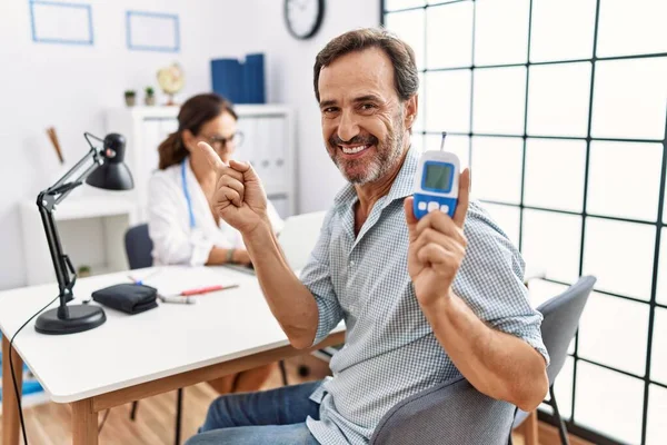 Homem Meia Idade Clínica Médica Segurando Dispositivo Medidor Glicose Sorrindo — Fotografia de Stock