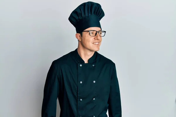 Όμορφος Νεαρός Άνδρας Φορώντας Επαγγελματική Στολή Μάγειρας Και Καπέλο Ψάχνει — Φωτογραφία Αρχείου