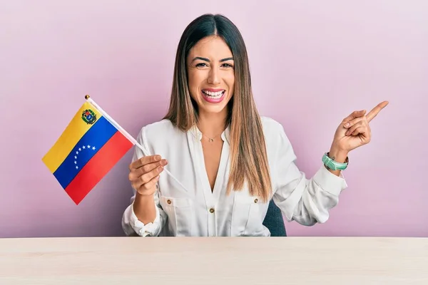 Молода Іспаномовна Жінка Тримає Венесуельський Прапор Сидячи Столі Усміхаючись Щасливо — стокове фото