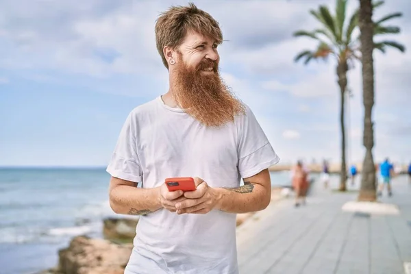 Ung Rödhårig Man Ler Glad Med Hjälp Smarttelefon Stranden — Stockfoto