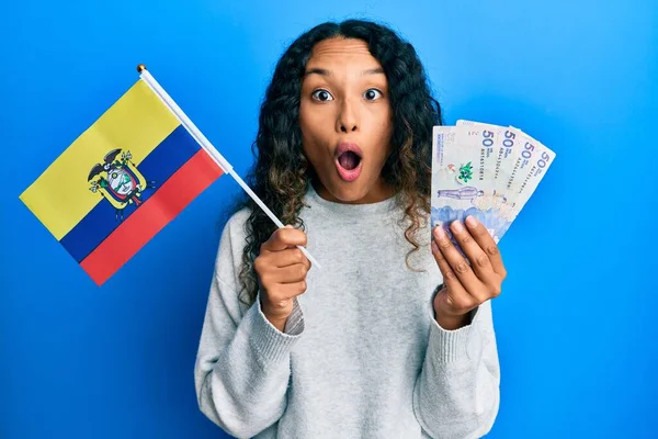 拿着哥伦比亚国旗和哥伦比亚比索钞票的年轻拉丁女子害怕 惊讶的表情 恐惧和激动的脸震惊了 — 图库照片