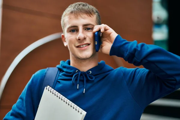 Młody Blond Student Rozmawiający Smartfonie Trzymając Notatnik Uniwersytecie — Zdjęcie stockowe
