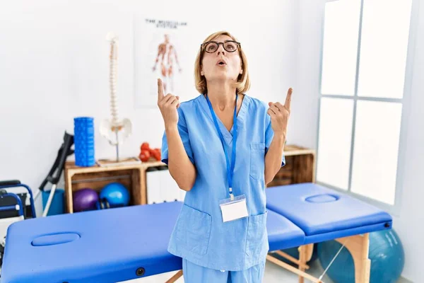 Mulher Loira Meia Idade Trabalhando Clínica Recuperação Dor Surpreso Surpreso — Fotografia de Stock