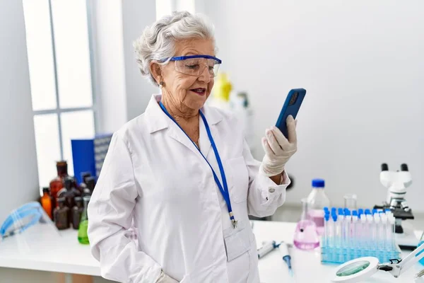 Starsza Siwowłosa Kobieta Mundurze Naukowca Używająca Smartfona Laboratorium — Zdjęcie stockowe