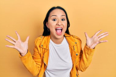 Sarı deri ceket giyen güzel İspanyol kadın çılgın kutlamalar yapıyor ve kollarını kaldırıp heyecanla haykırarak başarıyı kutluyor. Kazanan konsept 