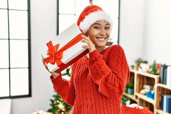 Jong Hispanic Vrouw Houden Geschenk Stand Door Kerstboom Thuis — Stockfoto